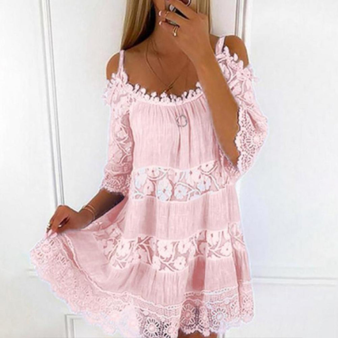 Vrouw in roze kanten zomerjurk met schouderbandjes en bloemenpatroon, perfect voor casual en strandkleding. Elegante en luchtige stijl.