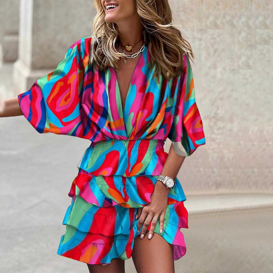Vrouw in kleurrijke, abstracte zomerjurk met korte mouwen en ruches, lachend op straat. Trendy damesmode, casual outfit, zomerse stijl.
