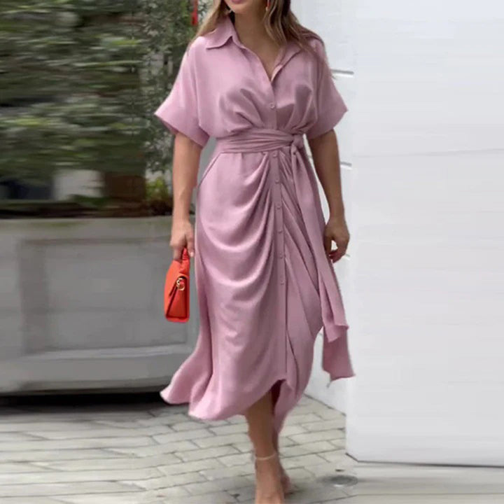 Vrouw in roze overhemdjurk met ceintuur, draagt een oranje handtas. Stijlvolle zomeroutfit, casual en elegant, perfect voor dagelijks gebruik.