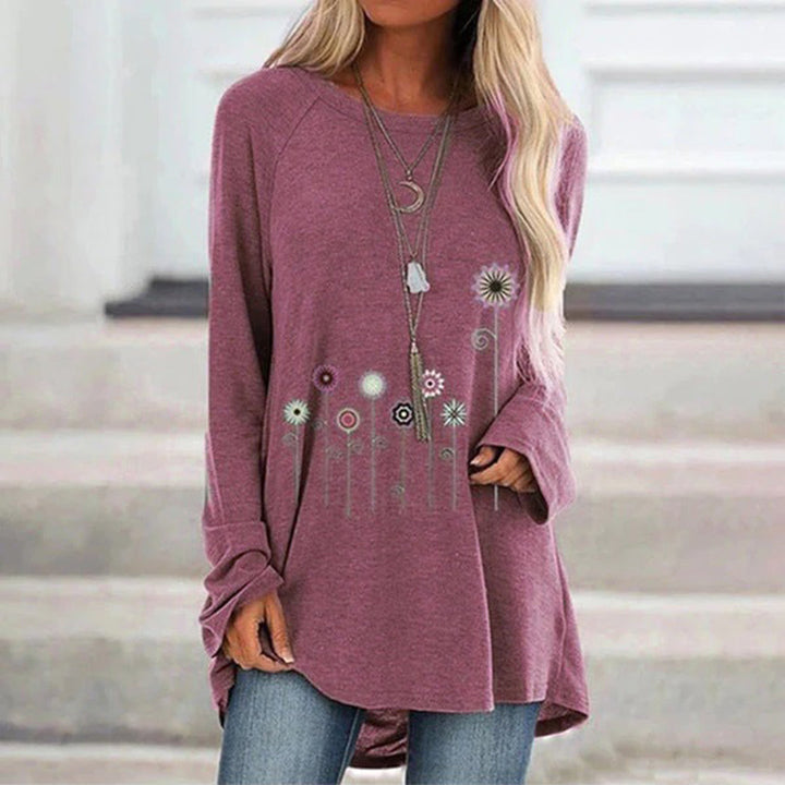 Vrouw draagt een roze oversized trui met bloemenprint en lange mouwen, gecombineerd met jeans. Casual damesmode, herfstkleding, trendy outfit.