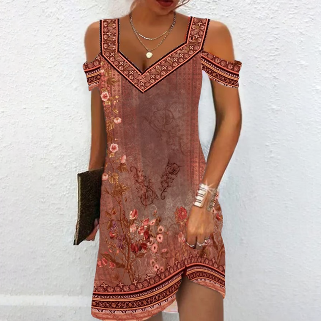 Vrouw in bohemian zomerjurk met bloemenprint, off-shoulder ontwerp, bruine tinten, tegen witte achtergrond. Perfect voor casual en stranduitjes.