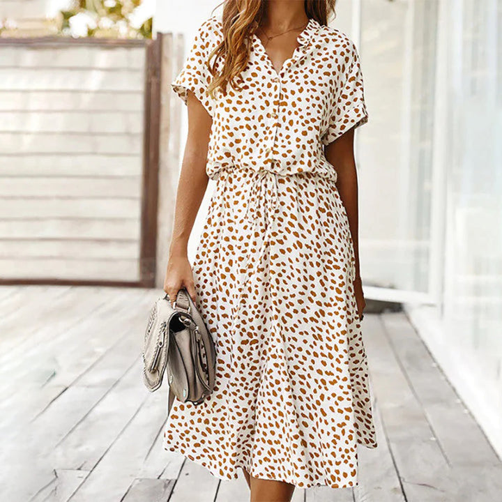 Vrouw in witte jurk met bruine luipaardprint, draagt grijze handtas. Zomermode, casual dameskleding, trendy outfit voor dagelijks gebruik.