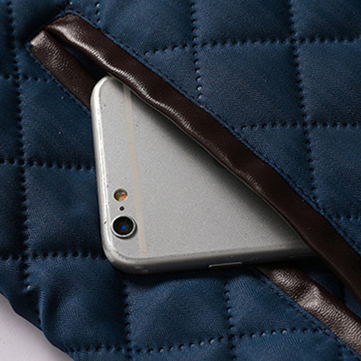 Grijze smartphone in blauwe gewatteerde tas met bruine leren rand. Stijlvolle telefoonaccessoire, moderne technologie, beschermhoes.