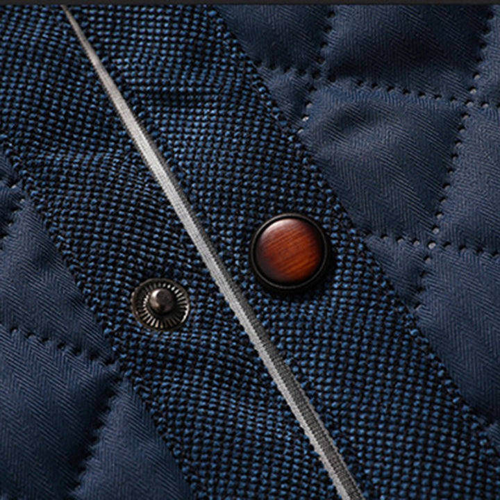 Donkerblauwe gewatteerde jas met metalen knopen en rits, close-up textuur. Stijlvolle winterjas, herenmode, hoogwaardige stof.