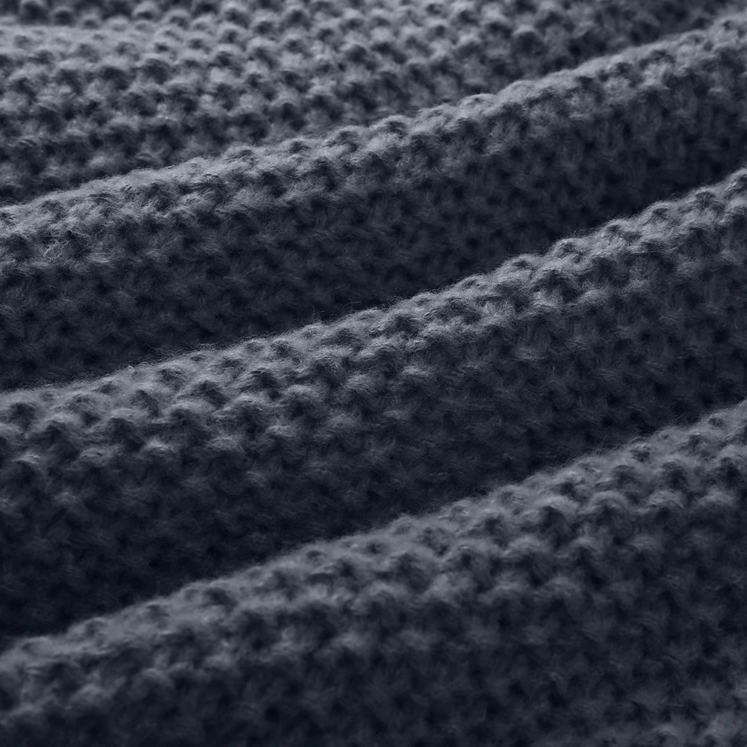 Donkergrijze gebreide stof met geribbelde textuur, close-up. Perfect voor warme truien en dekens. Hoogwaardige wol, duurzaam en stijlvol.