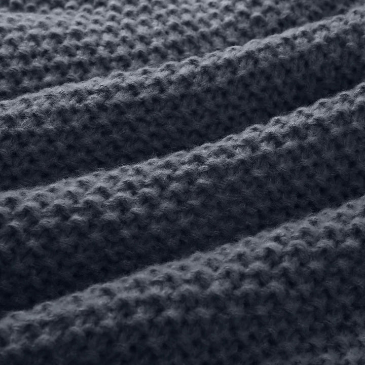 Donkergrijze gebreide stof met geribbelde textuur, close-up. Perfect voor warme truien en dekens. Hoogwaardige wol, duurzaam en stijlvol.