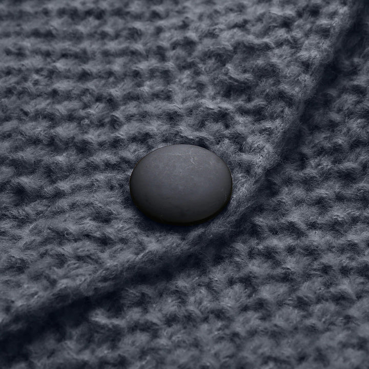 Donkergrijze gebreide stof met een ronde, matte zwarte knoop. Textuur en detail van de stof zijn duidelijk zichtbaar. Perfect voor mode- en textielontwerp.