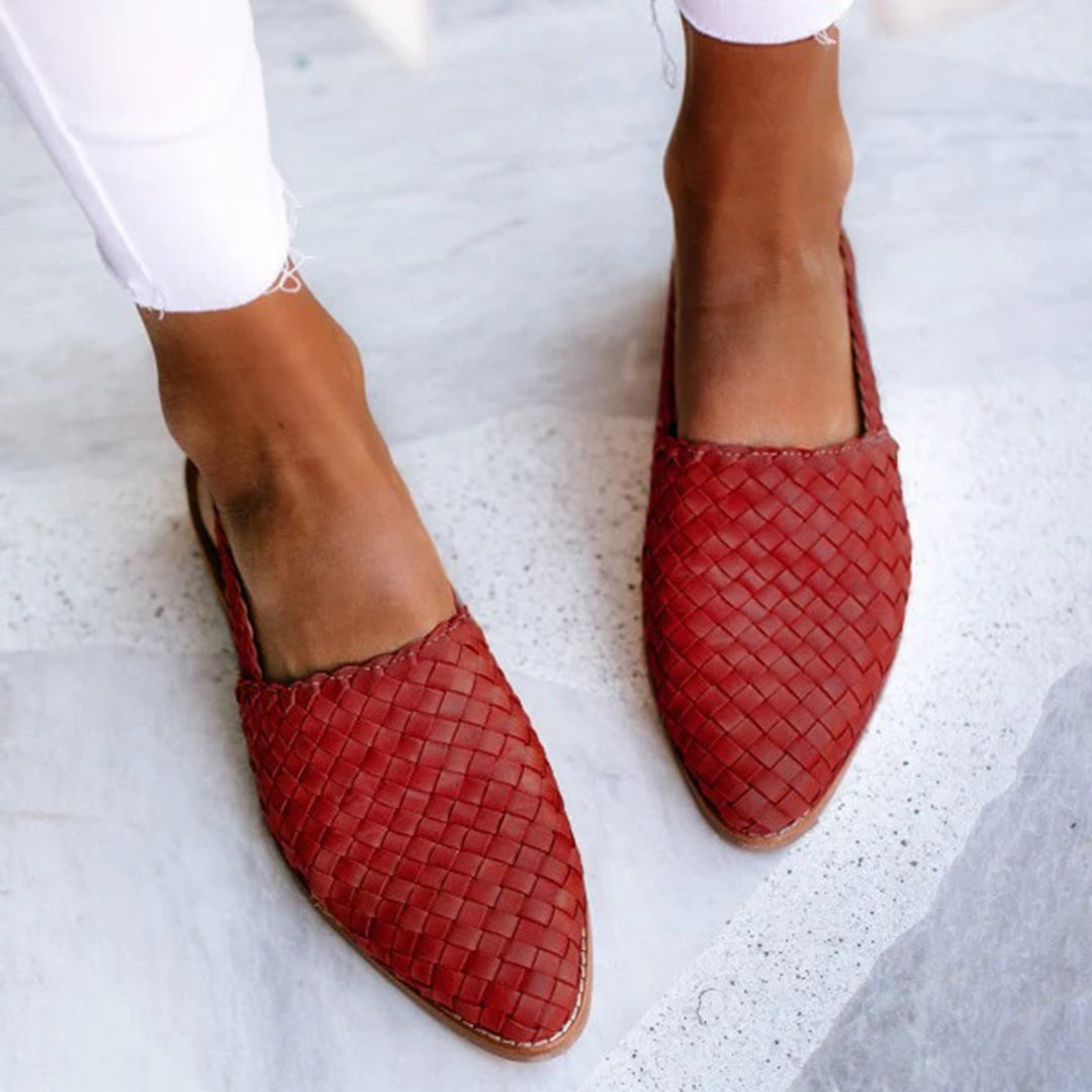 Rode gevlochten leren damesschoenen, stijlvolle instappers, gedragen op marmeren vloer. Perfect voor casual en elegante outfits.