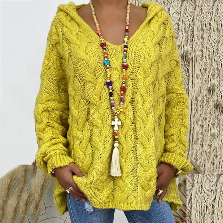 Gele gebreide trui met kabelpatroon, gedragen door model met kleurrijke kralenketting en spijkerbroek. Trendy herfstmode, comfortabele dameskleding.