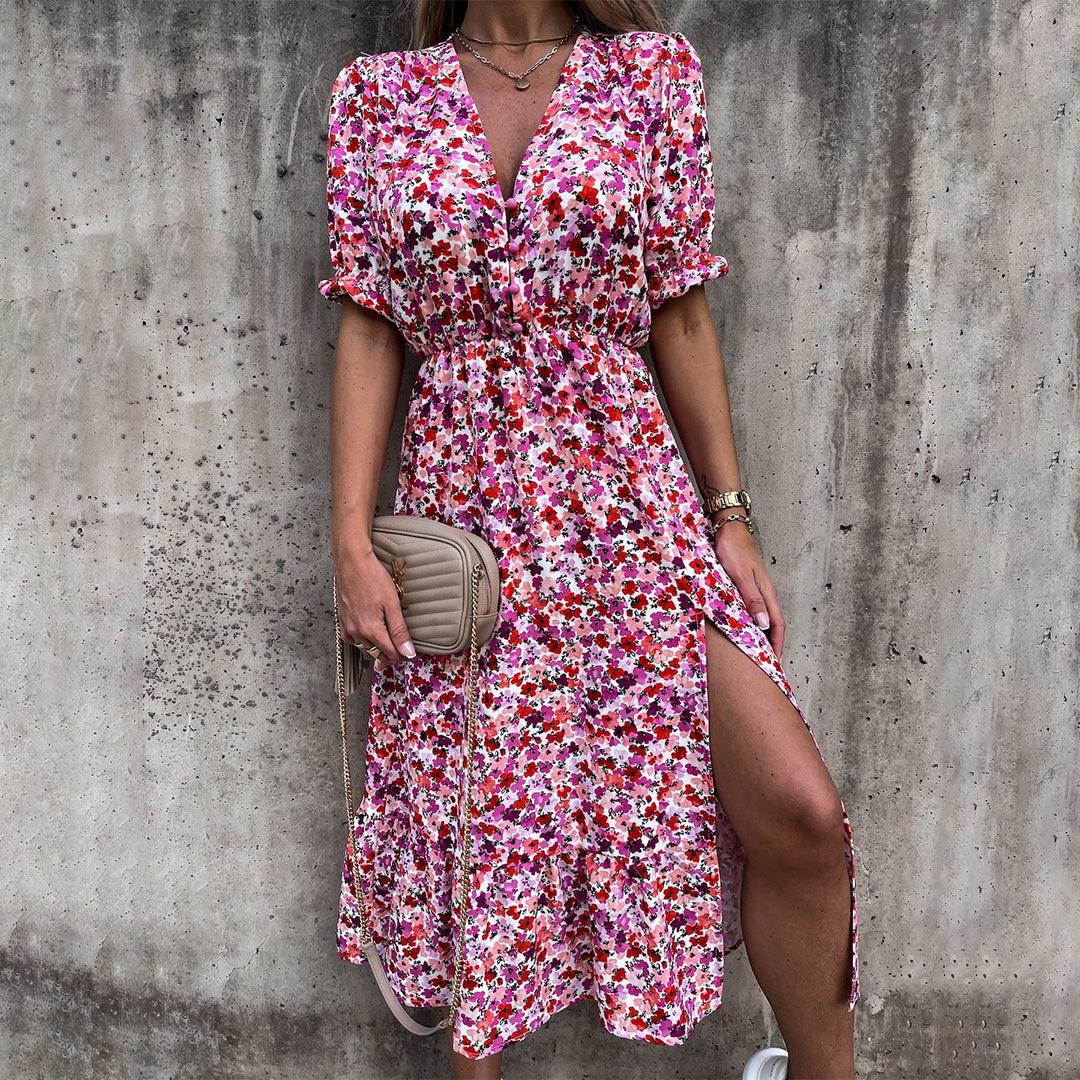 Vrouw in kleurrijke bloemenjurk met split, draagt een beige schoudertas. Perfecte zomeroutfit voor casual en elegante gelegenheden.