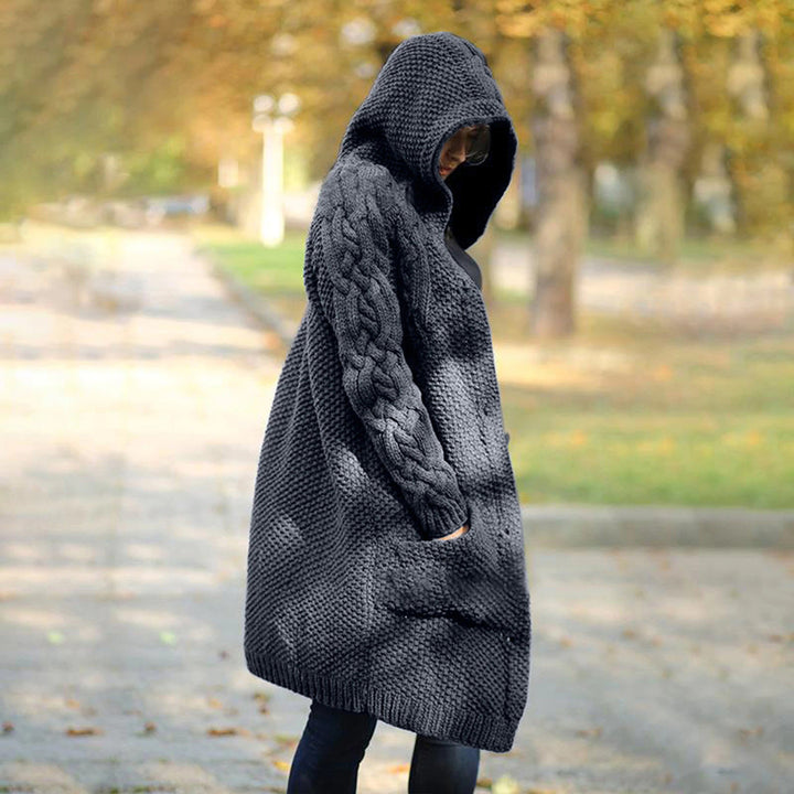 Grijze gebreide damesvest met capuchon, herfstmode, casual oversized stijl, warme wollen textuur, ideaal voor koel weer, buiten wandelen.