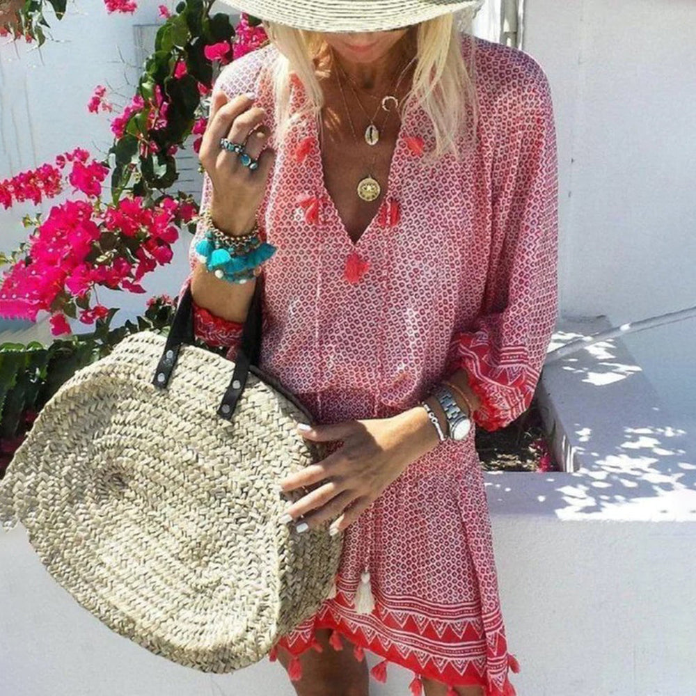 Vrouw in rode zomerjurk met strohoed en rieten tas, omringd door roze bloemen. Perfecte zomermode, boho-stijl, strandaccessoires.