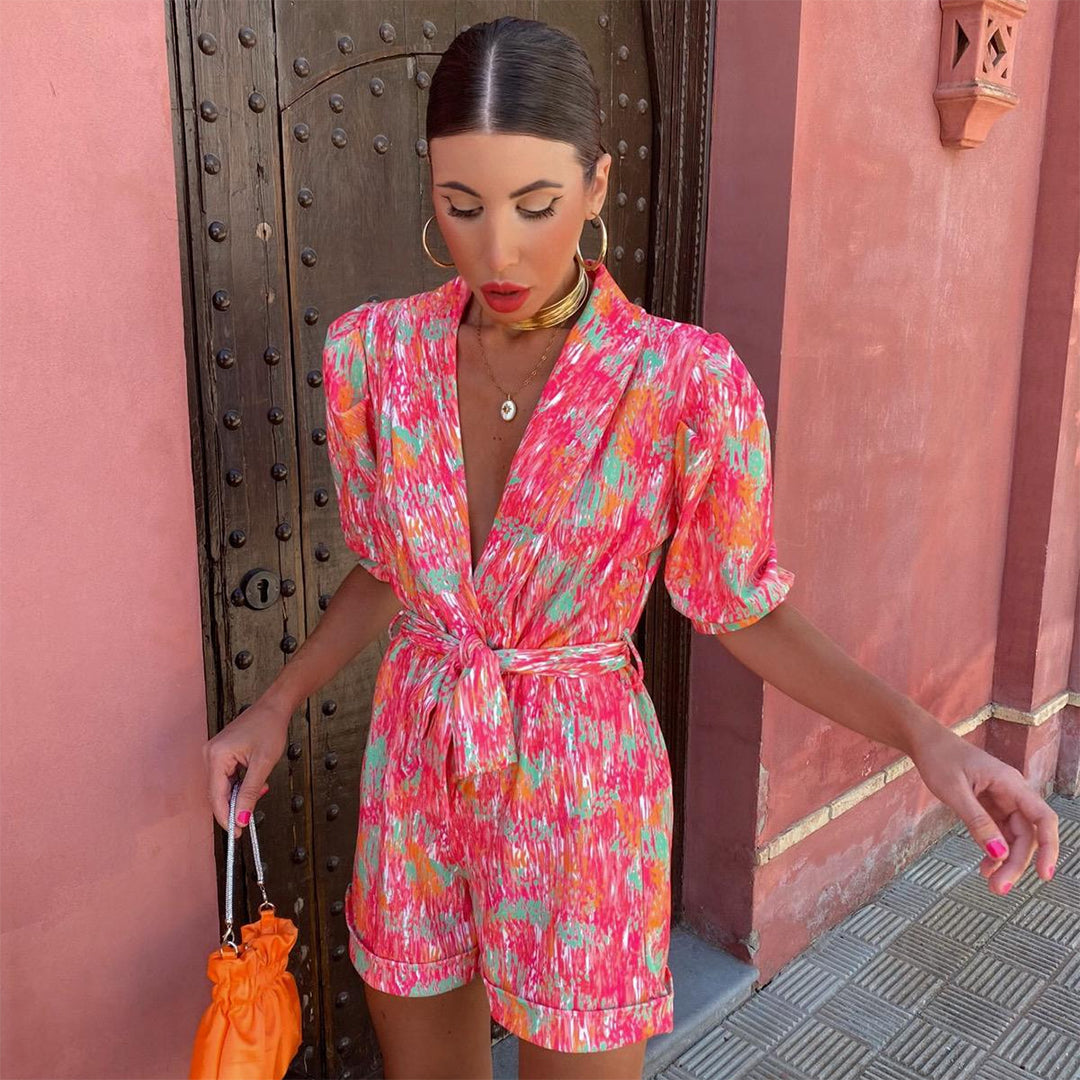 Vrouw in kleurrijke zomerjurk met abstract patroon voor antieke houten deur, draagt oranje tas. Mode, zomeroutfit, trendy kleding.
