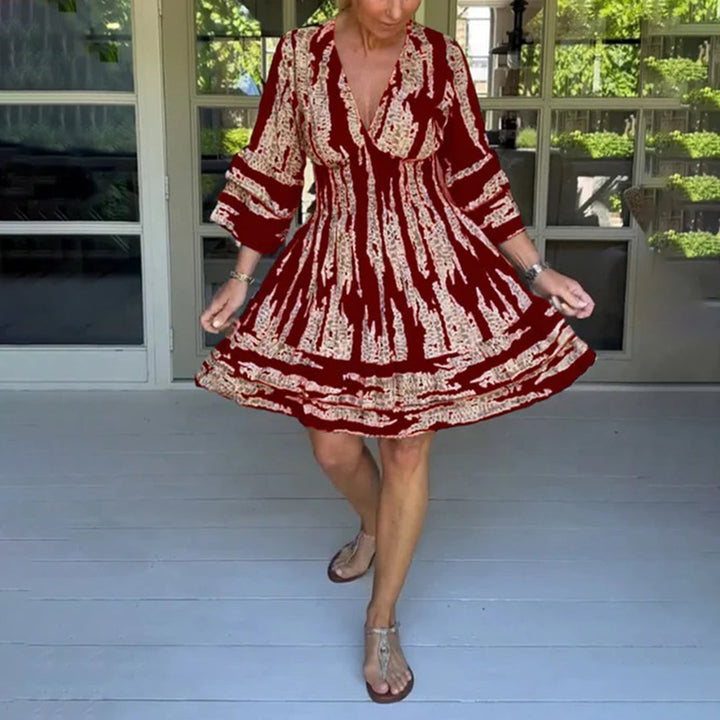 Vrouw in rode zomerjurk met witte patronen, staand op veranda. Modieuze dameskleding, casual stijl, comfortabele pasvorm, perfect voor warme dagen.