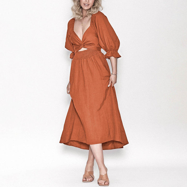 Oranje zomerjurk met diepe V-hals en pofmouwen, gedragen door een vrouw. Ideaal voor casual en elegante zomermode. Trendy dameskleding.
