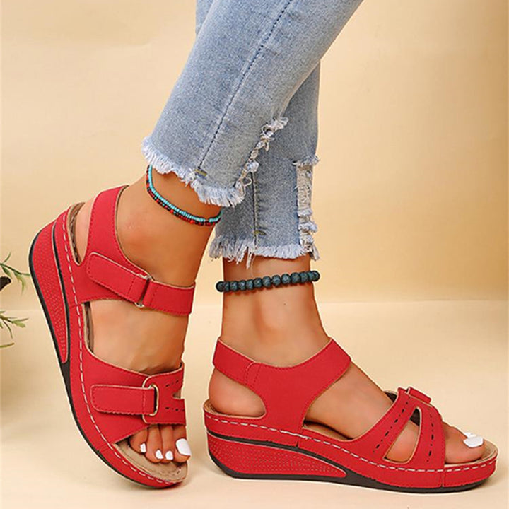 Rode dames sandalen met sleehak, verstelbare bandjes en comfortabele zool, gedragen met gescheurde jeans. Perfect voor zomerse casual outfits.