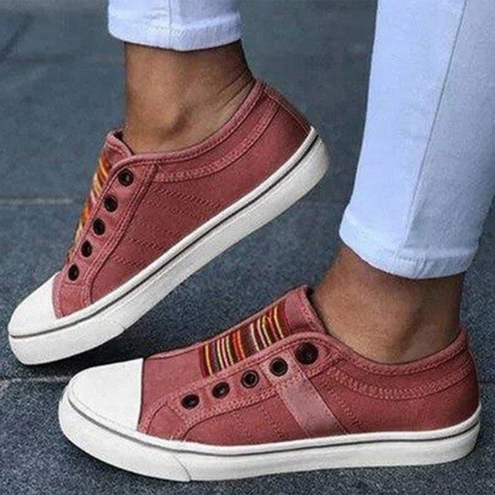 Rode sneakers met witte zolen en kleurrijke strepen, gedragen door persoon in witte broek. Modieuze casual schoenen voor dagelijks gebruik.