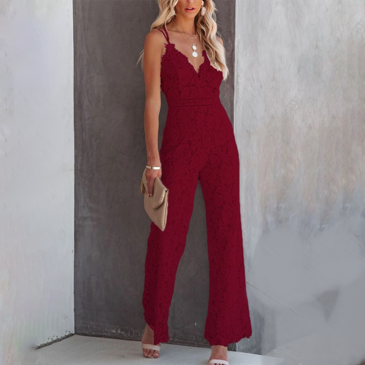 Vrouw in elegante rode jumpsuit met kanten details, poseert tegen grijze muur. Perfect voor avondkleding, mode, stijlvol, trendy outfit.