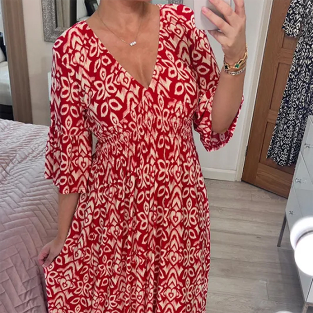 Vrouw in rode bohemian jurk met wit bloemenpatroon, selfie in slaapkamer. Trendy damesmode, casual zomerjurk, comfortabele pasvorm.