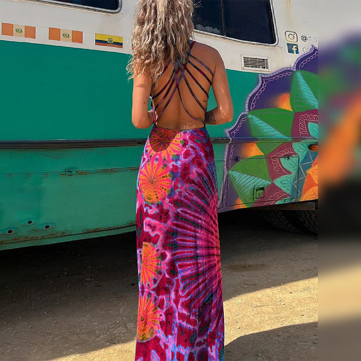 Vrouw in kleurrijke, rugloze maxi-jurk met abstract patroon, staand voor beschilderde bus. Zomermode, bohemian stijl, festival outfit.
