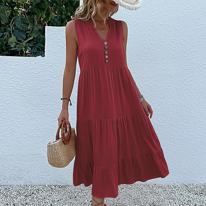 Vrouw in rode zomerjurk met knopen, rieten tas, en hoed, staand voor witte muur. Perfecte outfit voor zomerse dagen. Modieuze dameskleding.