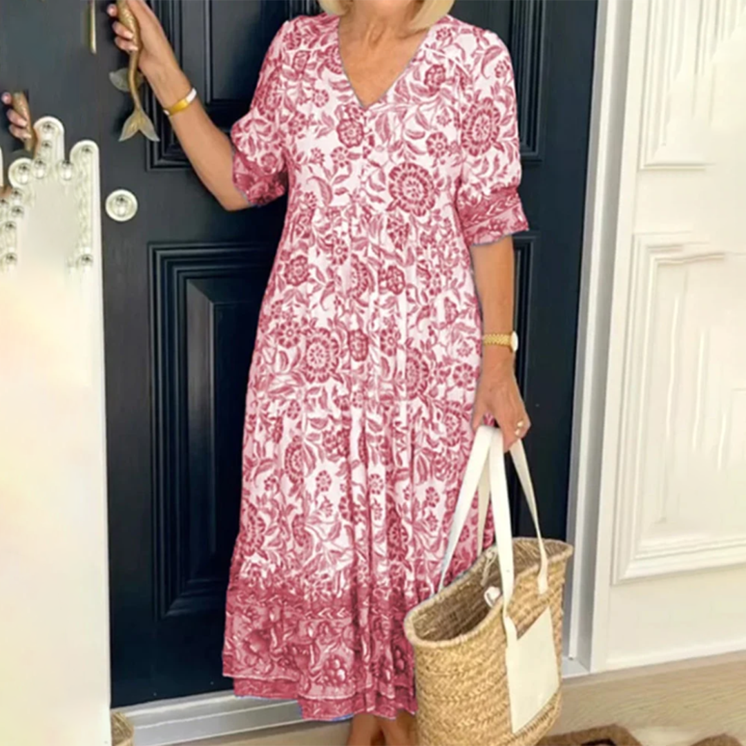 Vrouw in rode bloemenjurk met rieten tas voor zwarte deur. Zomerse boho-stijl, casual mode, dameskleding, trendy outfit.