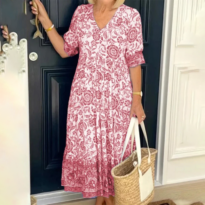 Vrouw in rode bloemenjurk met rieten tas voor zwarte deur. Zomerse boho-stijl, casual mode, dameskleding, trendy outfit.