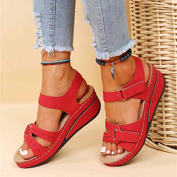 Rode dames sandalen met sleehak, verstelbare riem en open teen, gedragen met gescheurde jeans. Comfortabele zomerschoenen voor casual outfits.