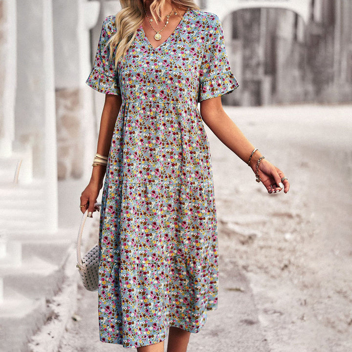 Vrouw in bloemenjurk met korte mouwen en V-hals, kleurrijk patroon, zomermode, casual stijl, buiten gefotografeerd op zonnige dag.