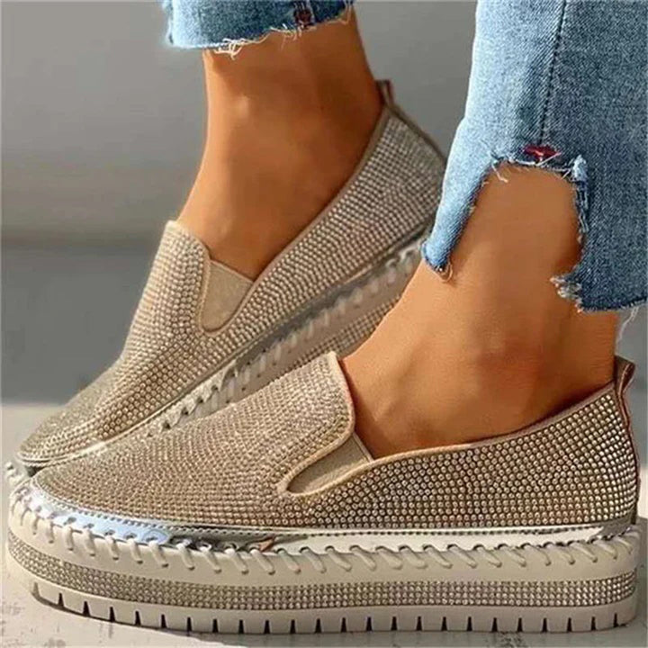 Zilveren damessneakers met strass, glanzende platformzool en gescheurde jeans. Modieuze, comfortabele schoenen voor dagelijks gebruik.