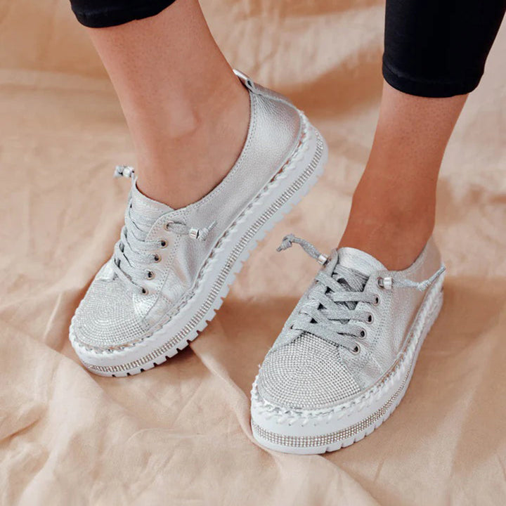 Zilveren damessneakers met veters, glanzende afwerking en dikke zool. Trendy en comfortabel schoeisel voor dagelijks gebruik.