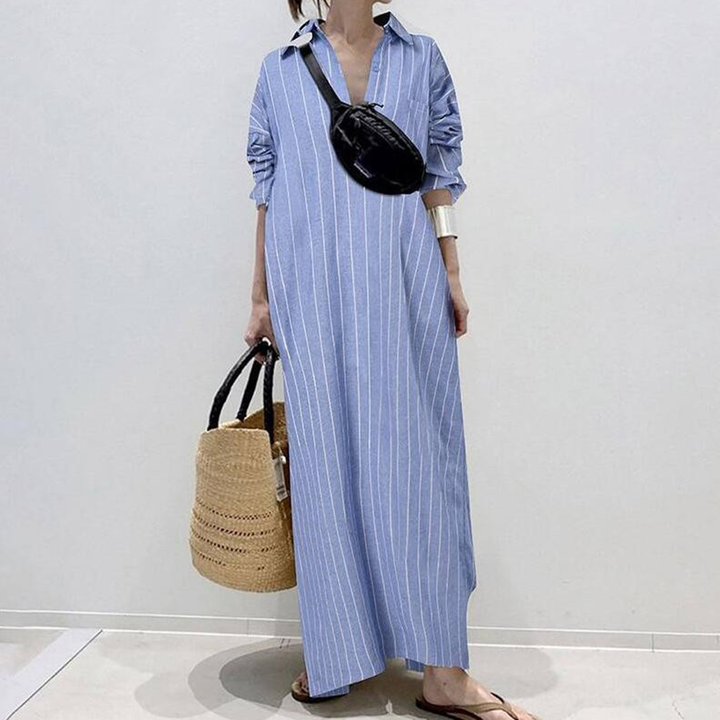 Vrouw in lichtblauwe gestreepte maxi-jurk met zwarte heuptas en rieten tas. Casual zomeroutfit, modetrend, comfortabele kledingstijl.