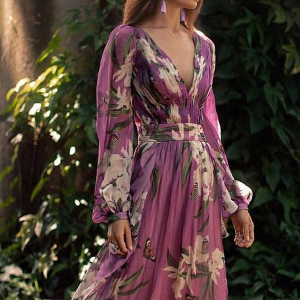 Elegante paarse maxi-jurk met bloemenprint en lange mouwen, perfect voor zomerfeesten. V-hals en vloeiende stof voor een stijlvolle look.