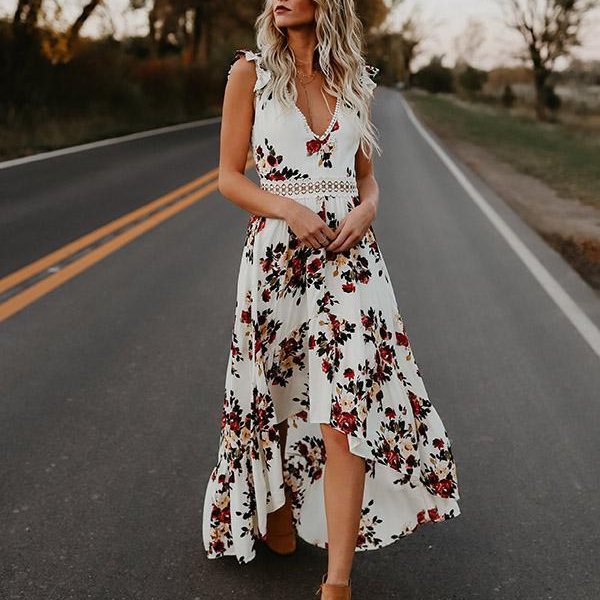 Vrouw in witte bloemenjurk met asymmetrische zoom op landelijke weg. Zomerjurk, bohemian stijl, casual mode, buiten fotoshoot.