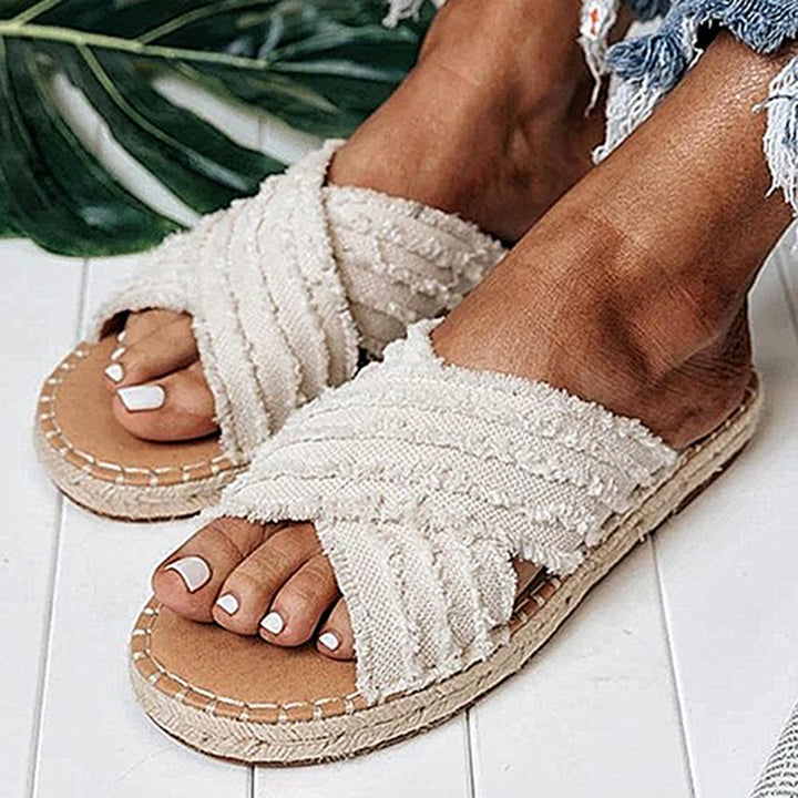 Witte dames sandalen met gevlochten bandjes, zomerse slippers op houten vloer, perfect voor strandmode. Comfortabele en stijlvolle zomerschoenen.