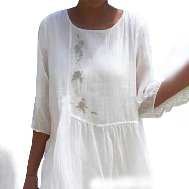 Witte damesjurk met driekwart mouwen en subtiele bloemenborduursels, ideaal voor zomerse dagen. Luchtige stof, casual en elegant design.