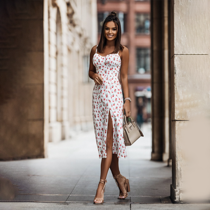 Witte zomerjurk met bloemenprint en split, gedragen door vrouw in stedelijke omgeving. Perfect voor casual en elegante zomermode.