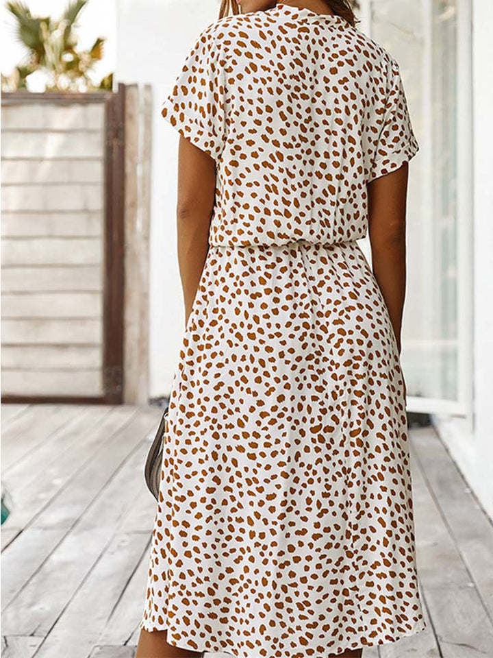 Vrouw in witte jurk met bruine stippen, zomerse mode, casual stijl, achteraanzicht, houten terras, trendy dameskleding.