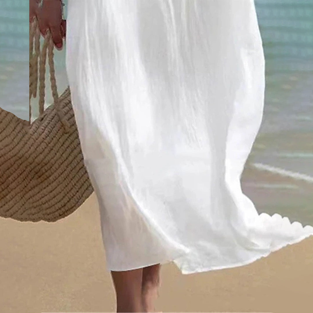 Witte zomerjurk op strand, vrouw met strooien tas. Perfect voor strandmode, casual zomerkleding, lichte en luchtige stijl.
