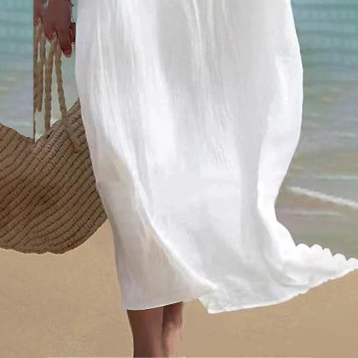 Witte zomerjurk op strand, vrouw met strooien tas. Perfect voor strandmode, casual zomerkleding, lichte en luchtige stijl.