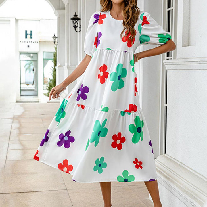 Vrouw in witte jurk met kleurrijke bloemenprint, korte mouwen en wijde rok. Perfect voor zomerse mode, casual en trendy stijl.