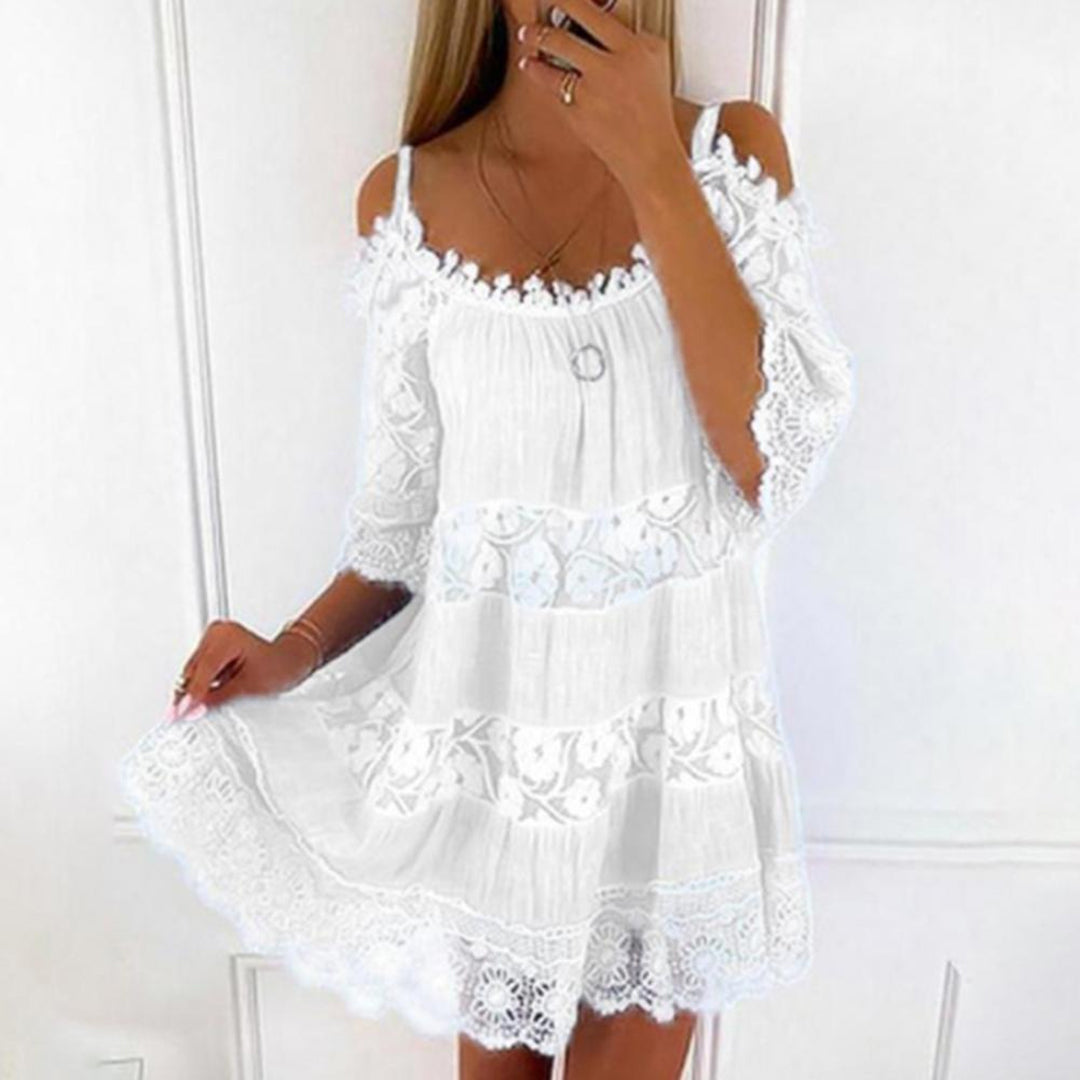 Witte kanten zomerjurk met schouderbandjes en bloemenpatroon, perfect voor strandmode. Elegante en luchtige dameskleding voor warme dagen.