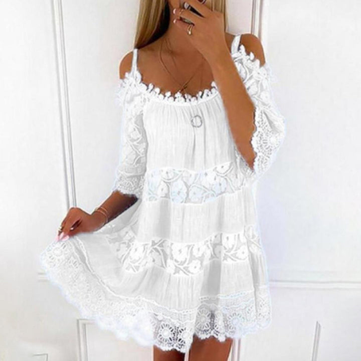 Witte kanten zomerjurk met schouderbandjes en bloemenpatroon, perfect voor strandmode. Elegante en luchtige dameskleding voor warme dagen.
