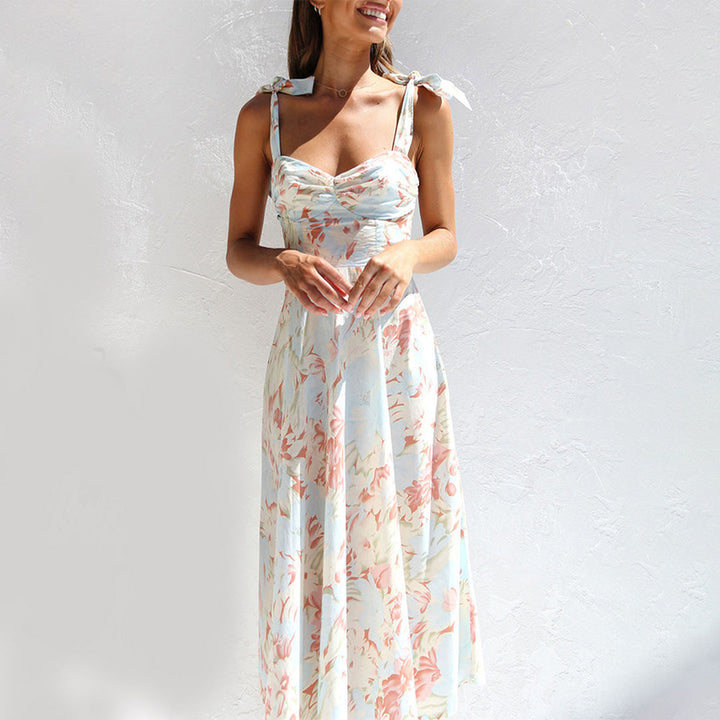 Vrouw in zomerse bloemenjurk met strikbandjes, pastelkleurig, ideaal voor casual en elegante gelegenheden. Perfecte keuze voor warme dagen.