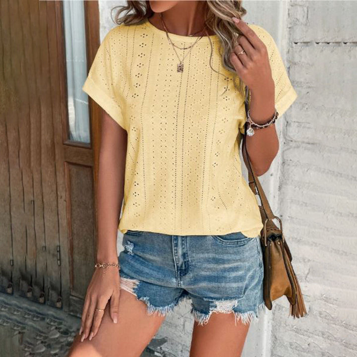 Vrouw in gele geperforeerde blouse en denim shorts, casual zomeroutfit, modeaccessoires, trendy dameskleding, buiten bij houten deur.