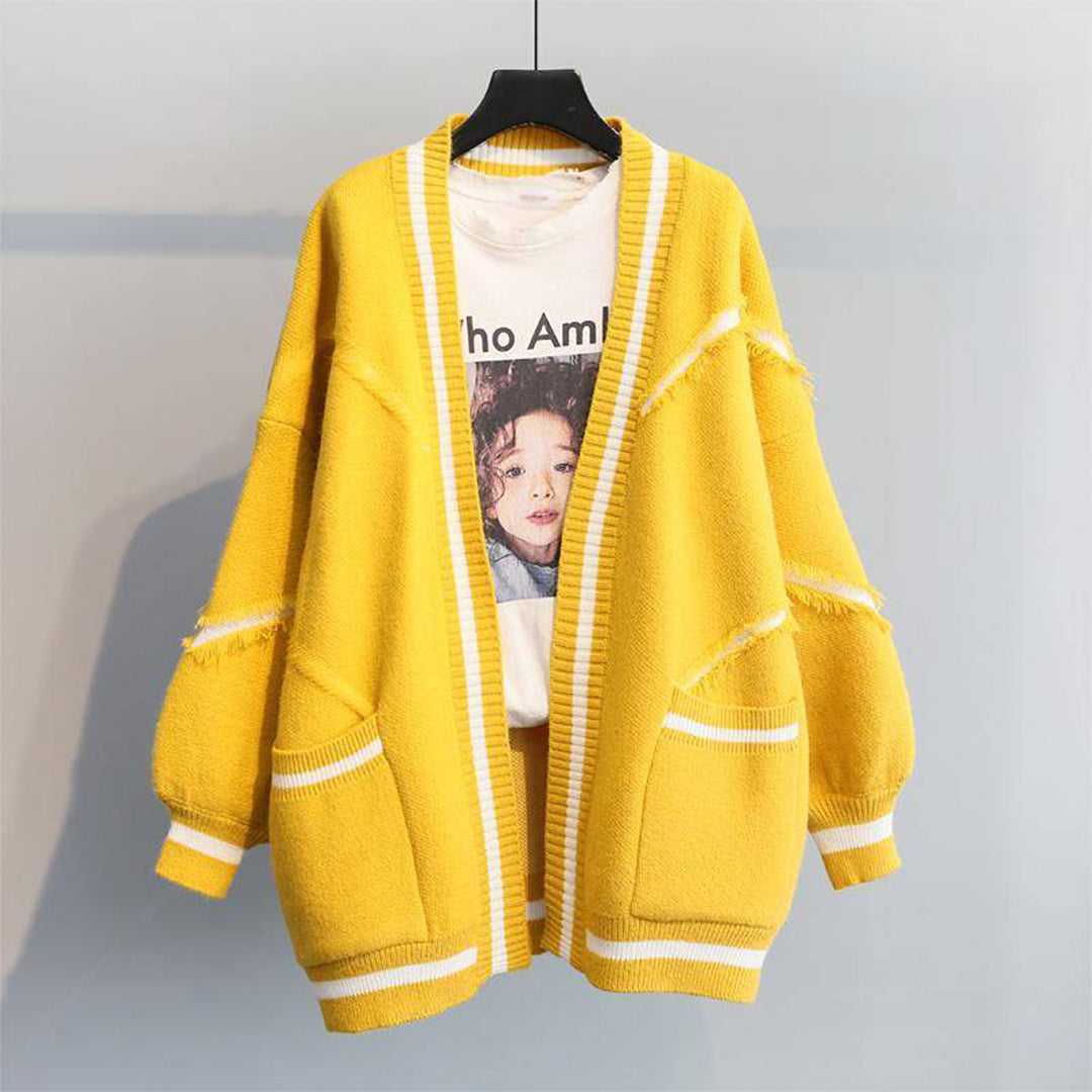Gele oversized cardigan met witte strepen, gerafelde details en zakken, gedragen over een T-shirt met kindergezicht. Trendy damesmode, herfstkleding.