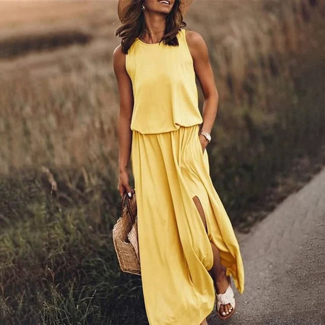 Vrouw in gele zomerjurk met hoed en rieten tas, wandelend op landweg. Zomeroutfit, casual mode, zonnige dag.