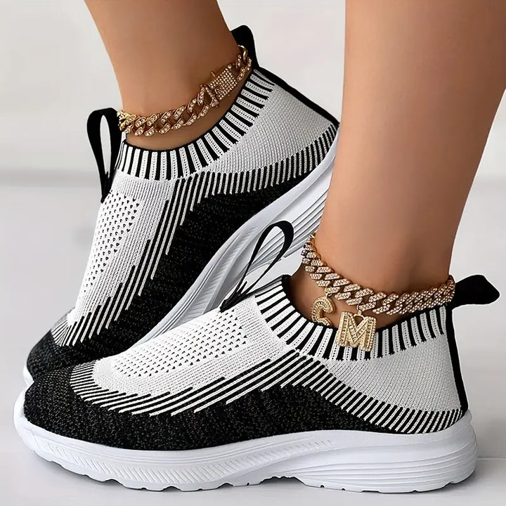Zwart-witte sneakers met gebreid patroon, comfortabele zool en gouden enkelbandjes. Trendy damesmode, sportieve schoenen, casual stijl.