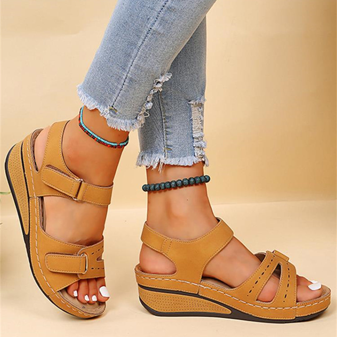 Bruine sandalen met sleehak, verstelbare bandjes en klittenbandsluiting, gedragen met gescheurde jeans. Comfortabele zomerschoenen voor dames.