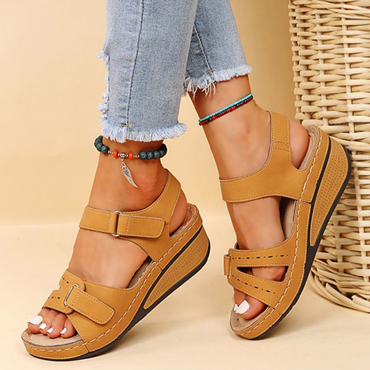 Bruine dames sandalen met klittenband, comfortabele sleehak, casual zomerschoenen, gedragen met lichtblauwe jeans, boho armband.